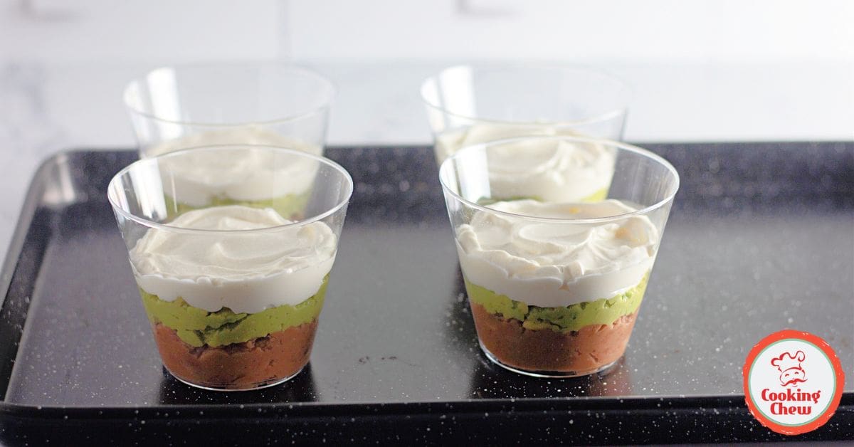 Close-up of 7 layer dip cups featuring guacamole and fresh toppings.