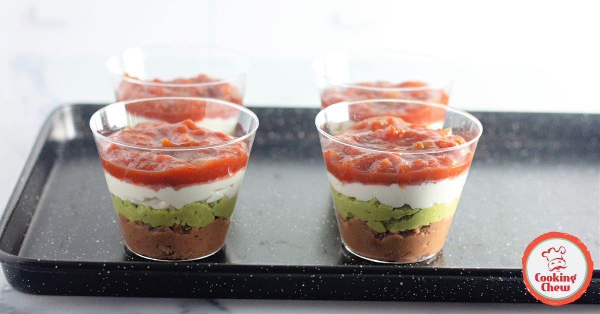 Individual layered Tex-Mex dip cups served with tortilla chips.