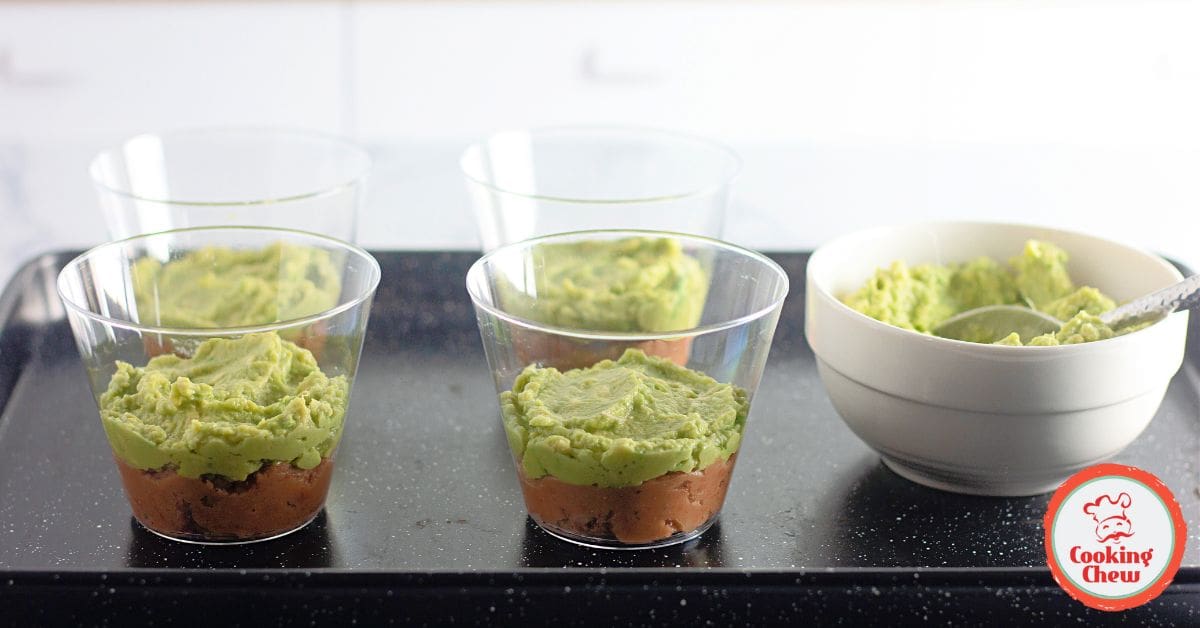 Single-serve 7 layer dip cups garnished with shredded cheese and fresh cilantro.