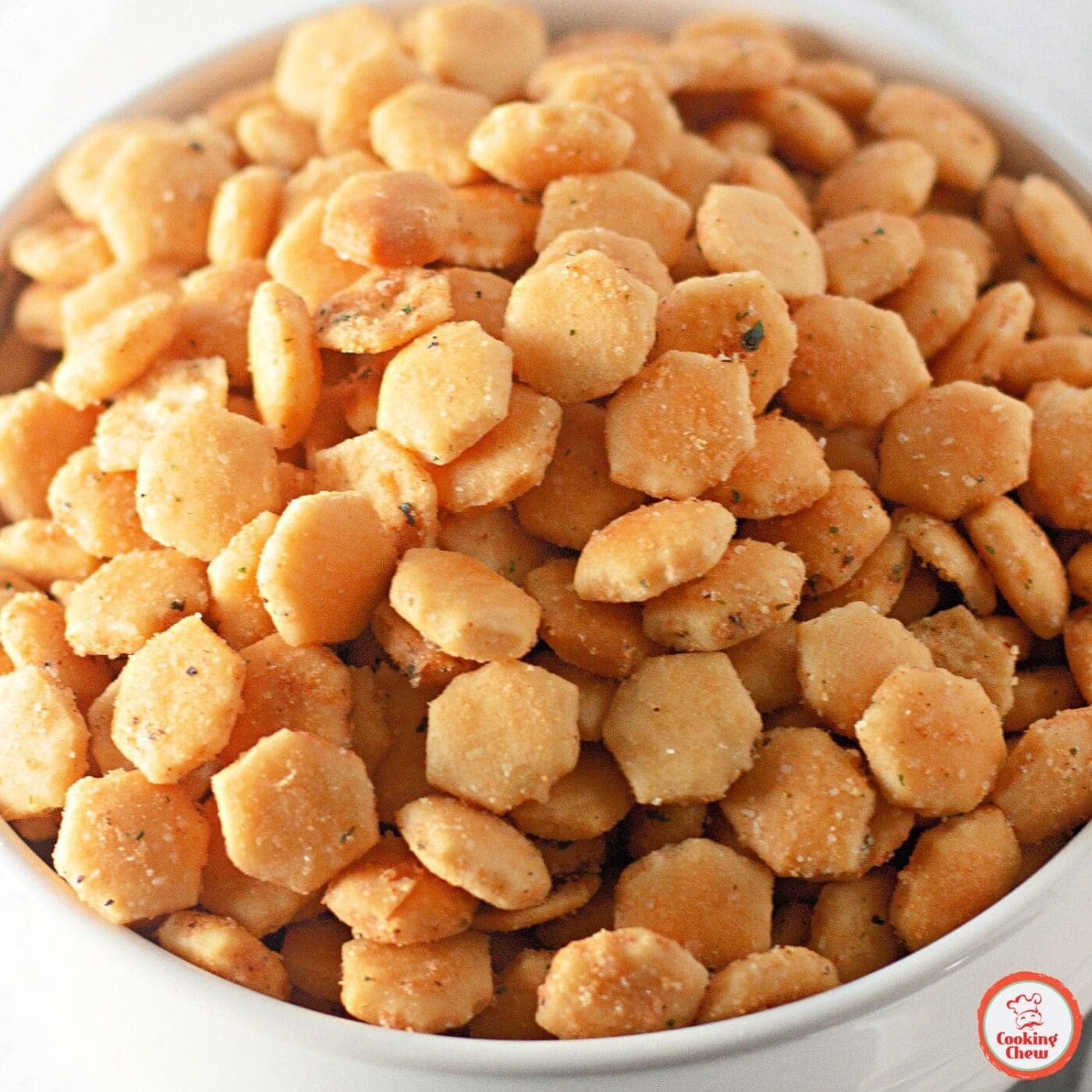 A wooden bowl filled with ranch oyster crackers on a dining table.