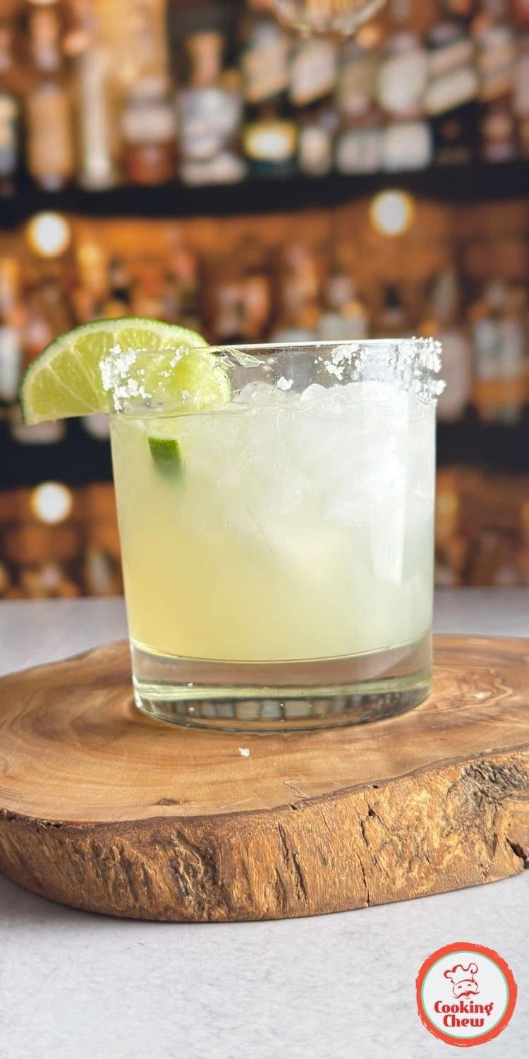 A close-up of a margarita glass filled with a golden-hued drink, rimmed with salt.