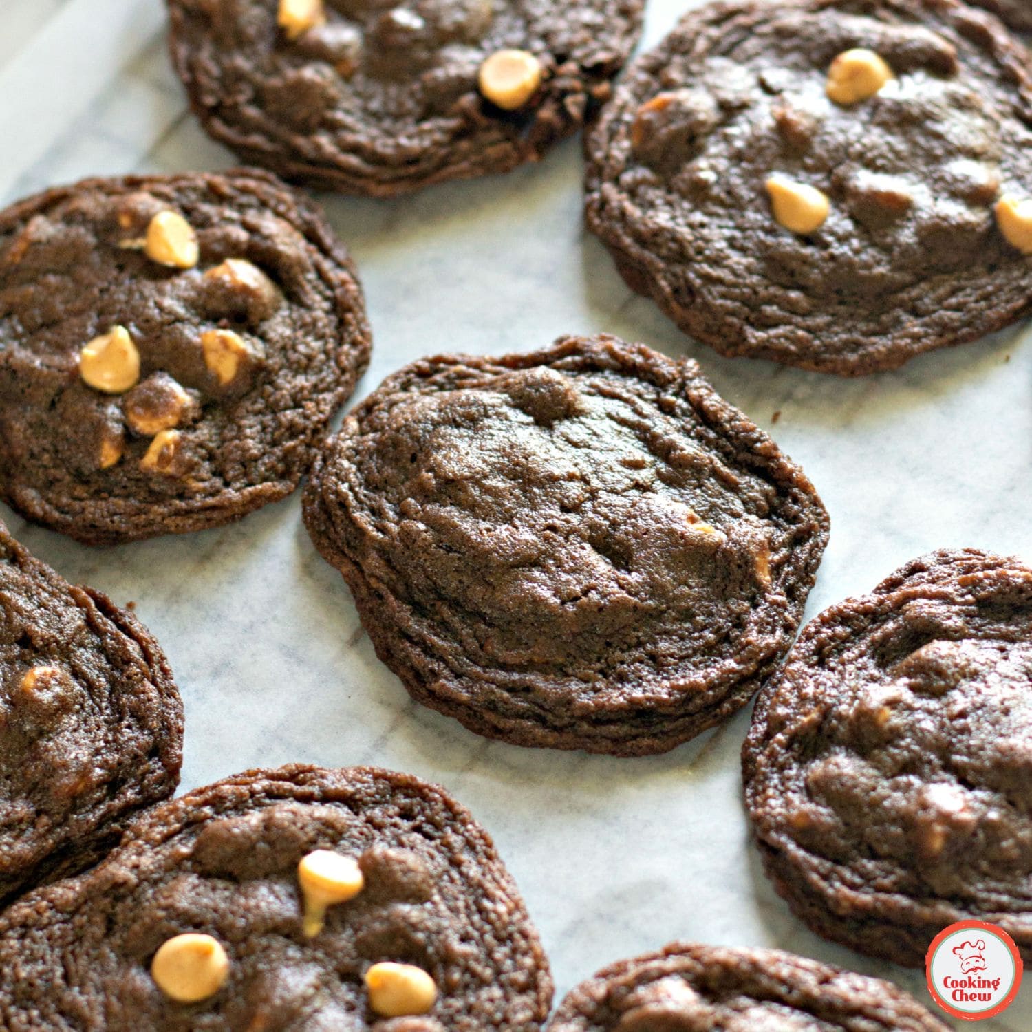 A plate of soft and chewy chocolate peanut butter chip cookies, with one cookie broken in half.