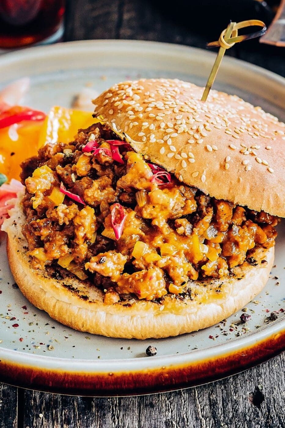 A hearty sloppy joe sandwich on a toasted bun, filled with rich, saucy ground beef and garnished with fresh herbs.