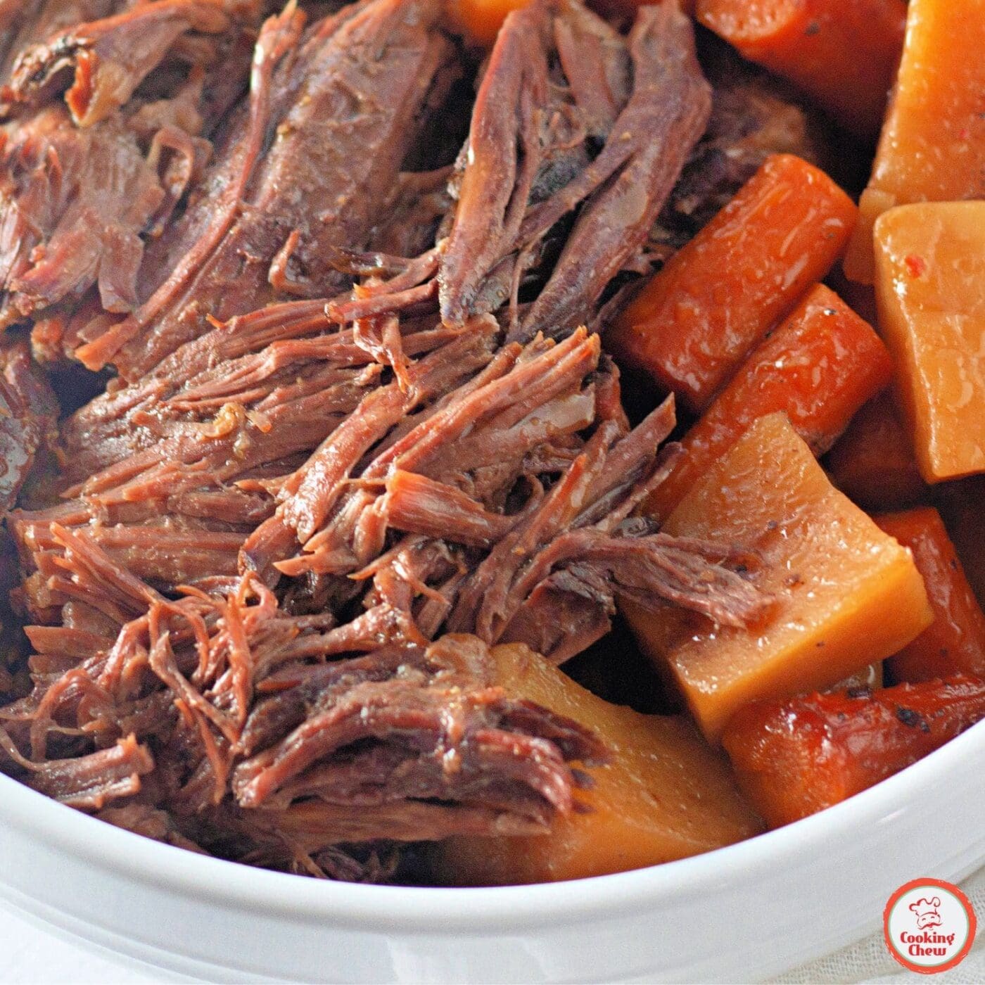 A plate of slow-cooked beef roast with vegetables and mashed potatoes.