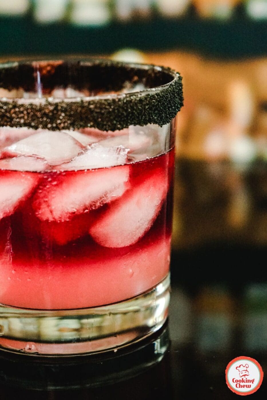 A BlackPink cocktail in a sleek glass, garnished with a pink cherry and lime, with a vibrant pink hue.