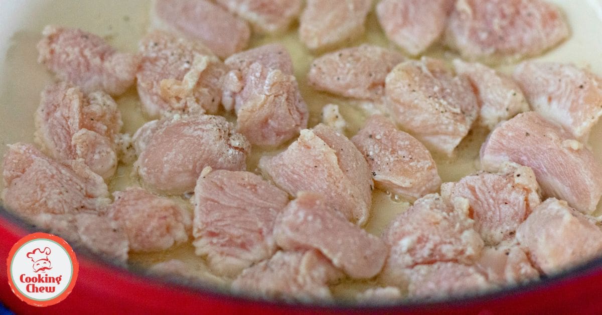 A spoon drizzling bourbon sauce over golden-brown chicken pieces.