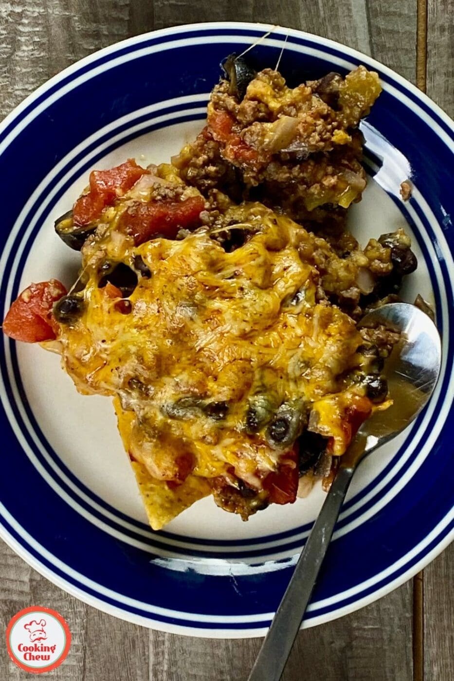 A bubbly, golden taco casserole topped with melted cheese, tomatoes, and fresh cilantro in a baking dish.