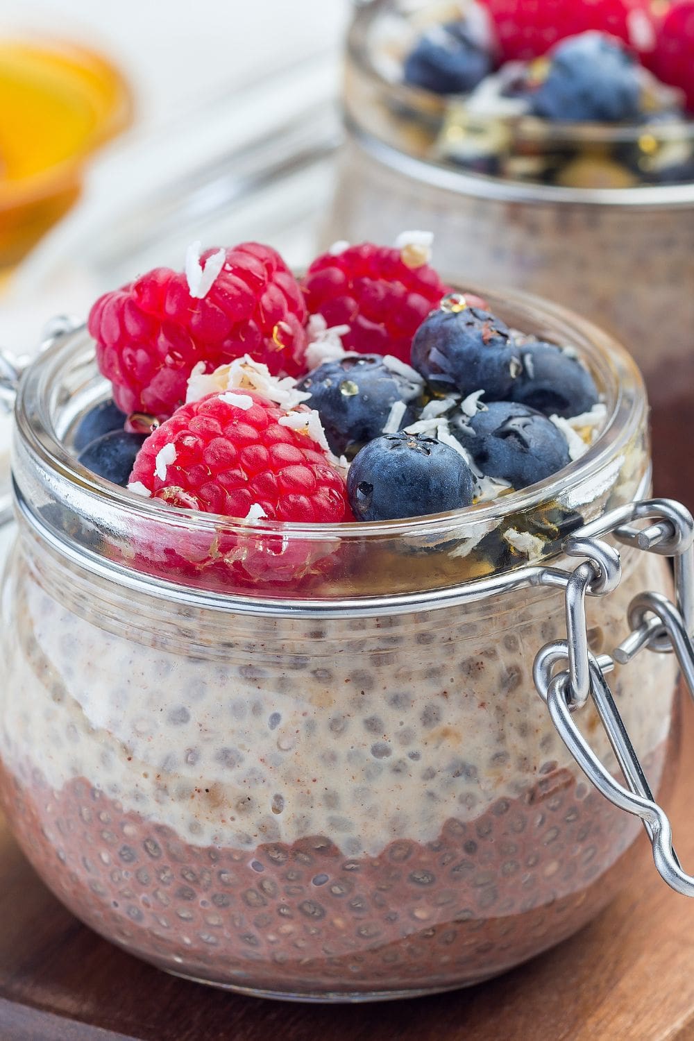 A jar of chocolate peanut butter chia pudding topped with chopped nuts and drizzled peanut butter, served on a rustic wooden table.