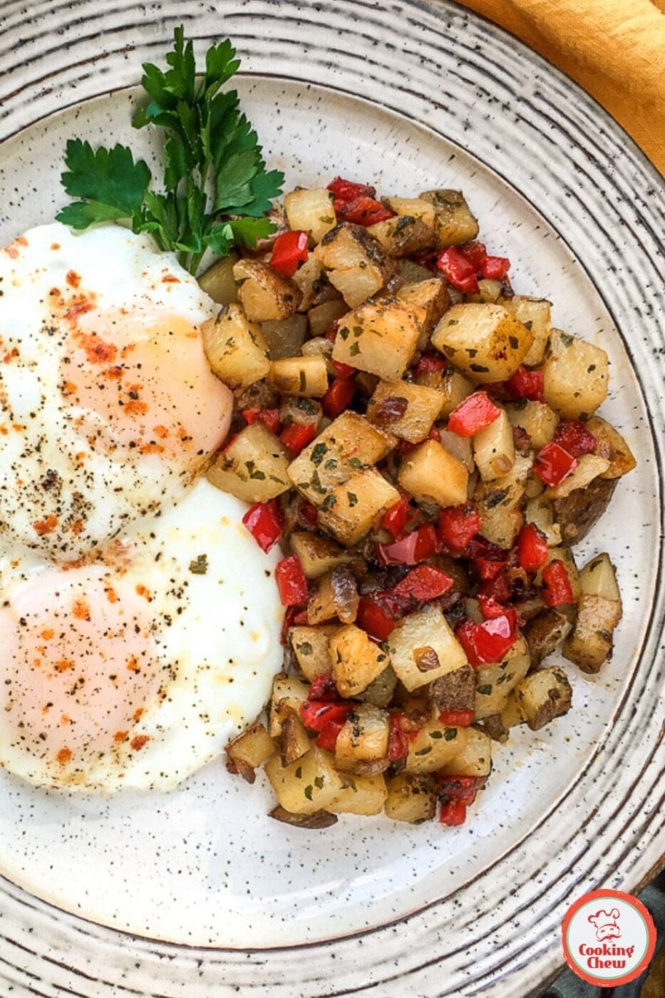 A plate of crispy, golden Parmesan breakfast potatoes, garnished with fresh herbs and served as a delicious morning side