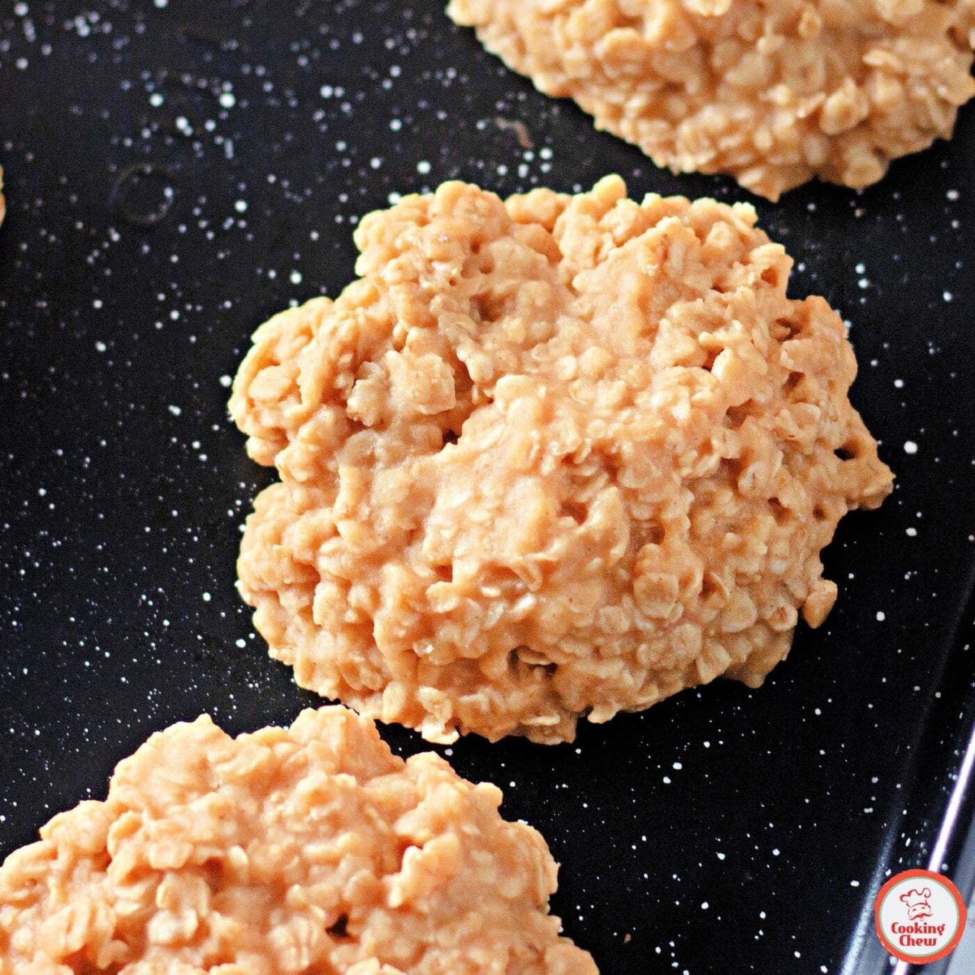 A plate of golden peanut butter no bake cookies with a cup of milk.