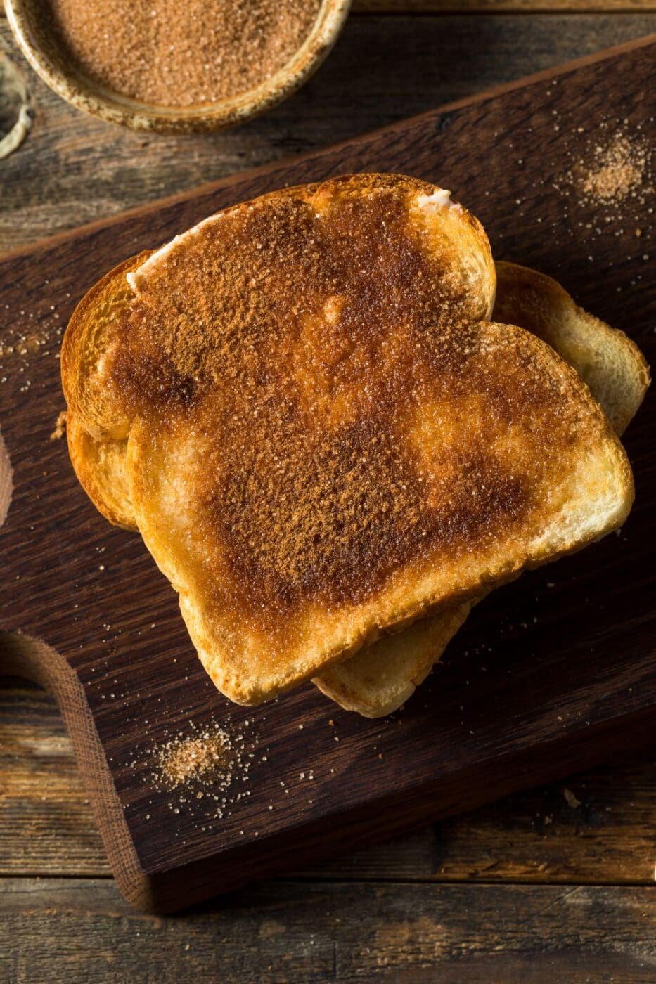 A slice of golden, crispy cinnamon toast with a buttery, spiced sugar topping on a plate.