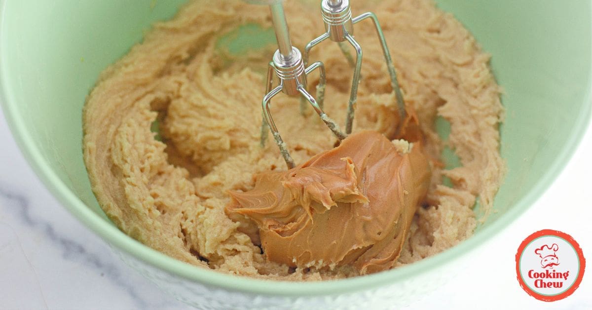 A close-up of chewy peanut butter bars stacked on parchment paper.