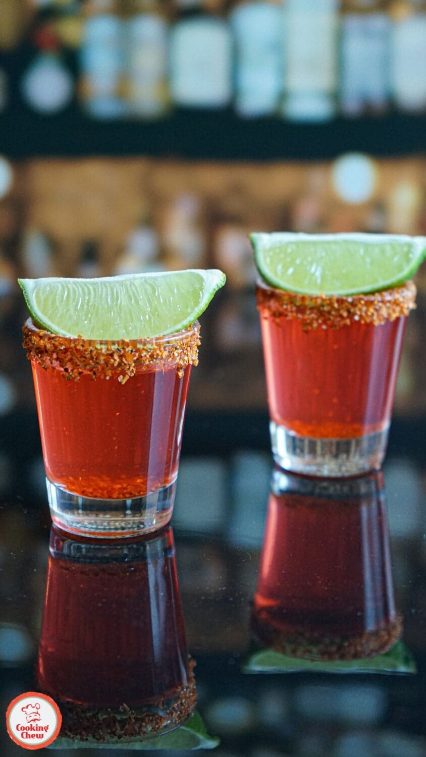 Close-up of a Spicy Mexican Candy Shot with a salted Tajín rim and a juicy lime wedge.