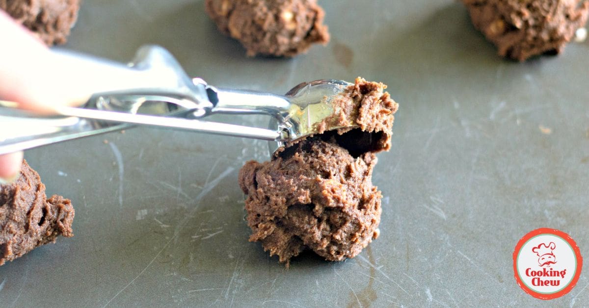 A mixing bowl filled with chocolate cookie dough with peanut butter chips ready to be scooped onto a baking sheet.