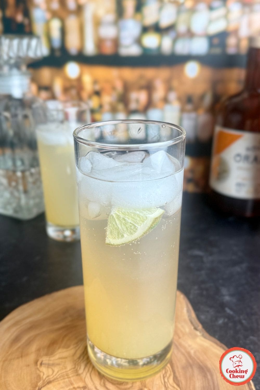 A glass of jalape&ntilde;o lime cocktail with ice, garnished with a lime wedge and jalape&ntilde;o slices.