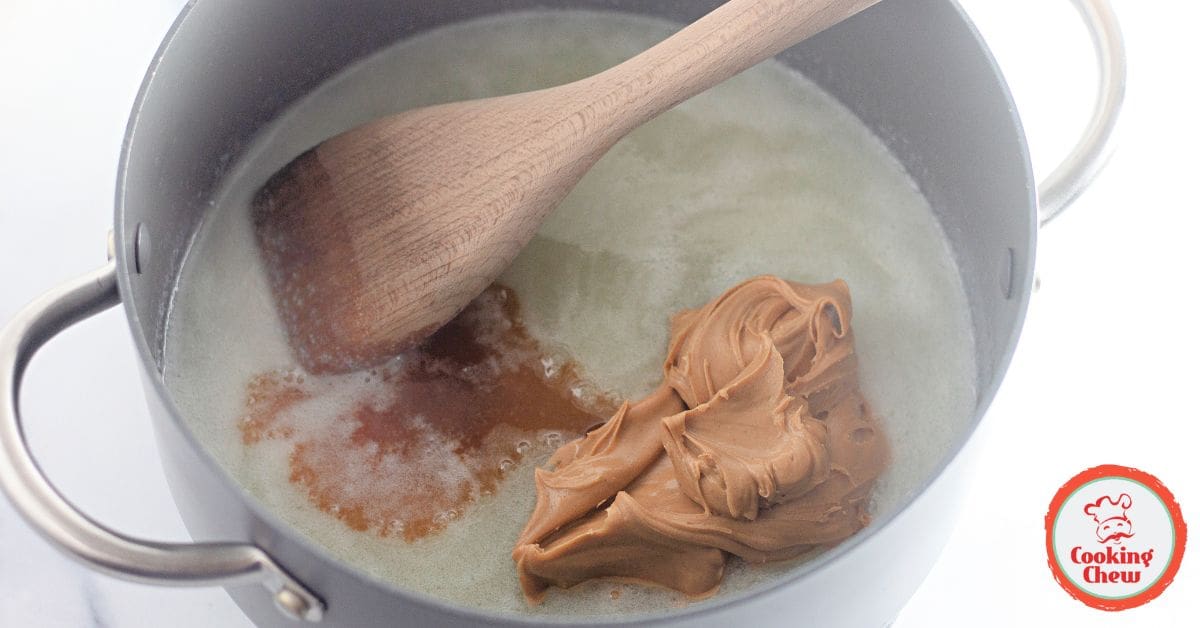 A spoon spreading melted peanut butter on no bake cookie dough.