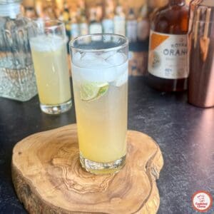 A cocktail glass filled with ice, lime, and jalapeño slices, with condensation on the rim.