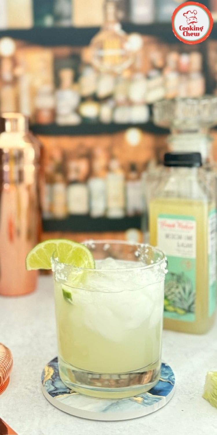 A refreshing lime margarita on the rocks with ice cubes and a salted rim, surrounded by lime slices.