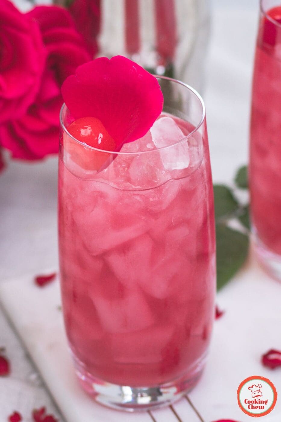 A stunning Rose World Cocktail with a delicate pink hue, garnished with rose petals in an elegant glass.
