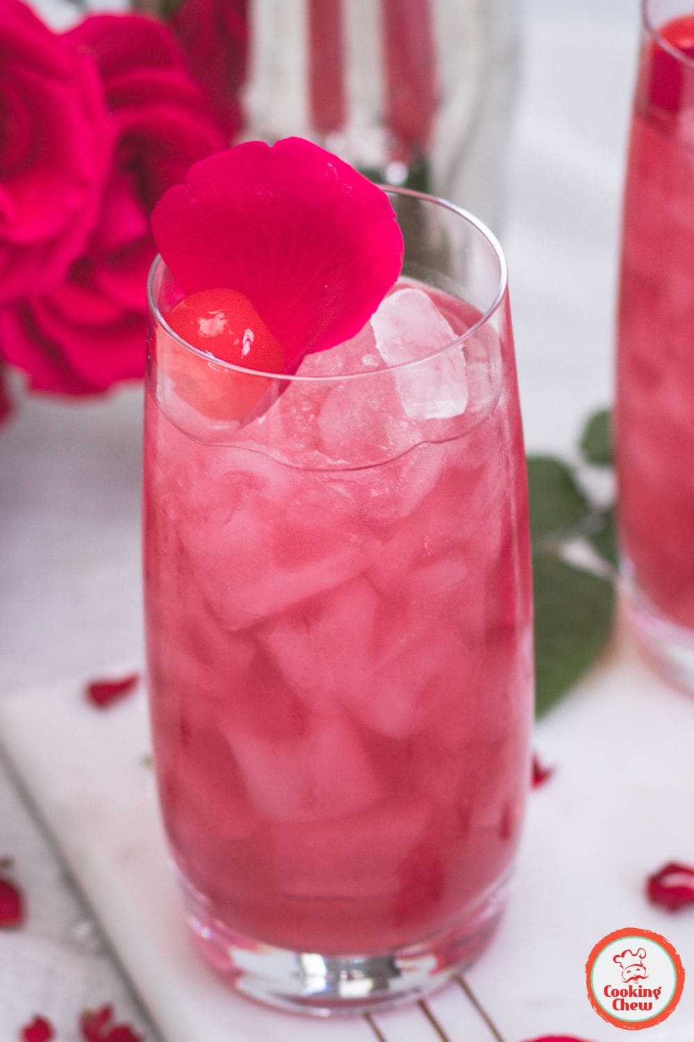 A stunning Rose World Cocktail with a delicate pink hue, garnished with rose petals in an elegant glass.