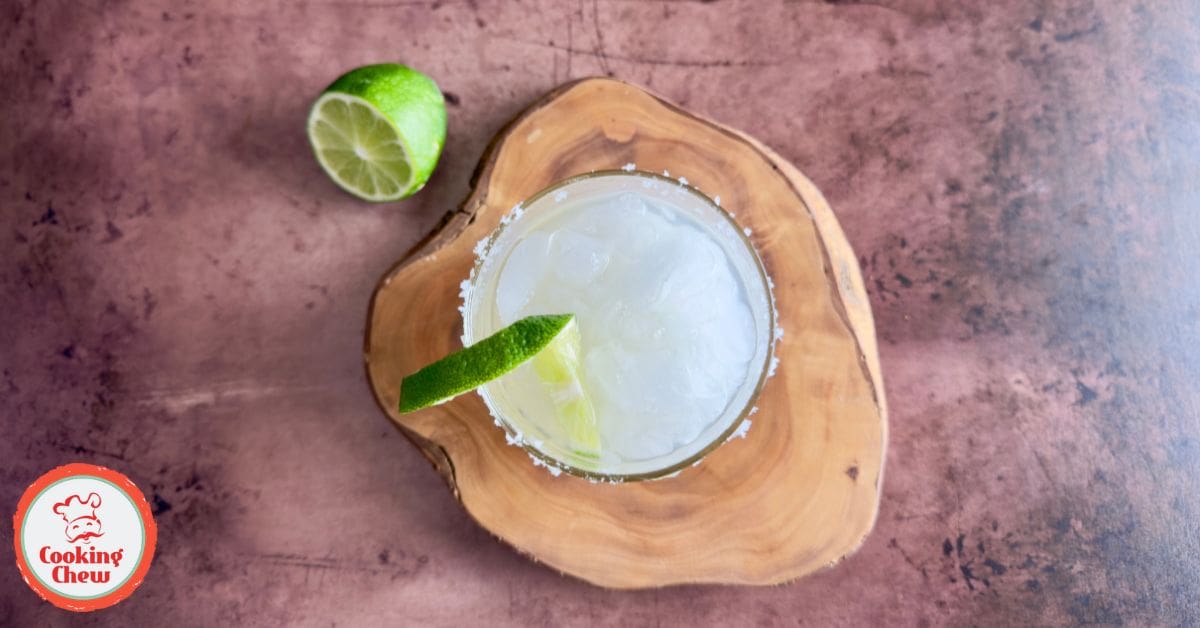 A freshly poured margarita cocktail in a glass, served with lime and a salted rim.