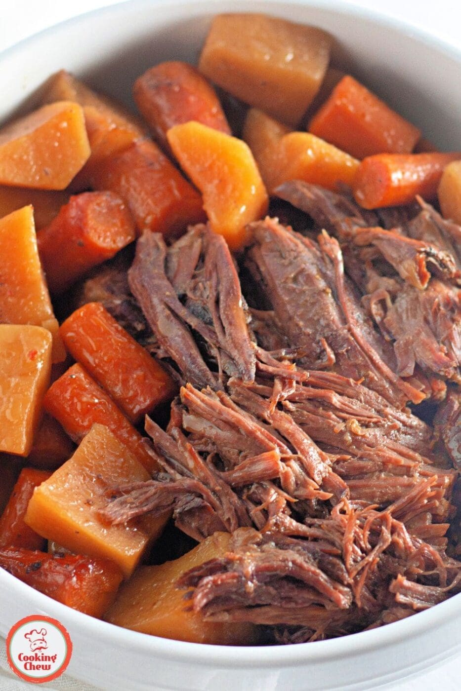 A tender beef roast with rich gravy, served with potatoes and carrots from a slow cooker.