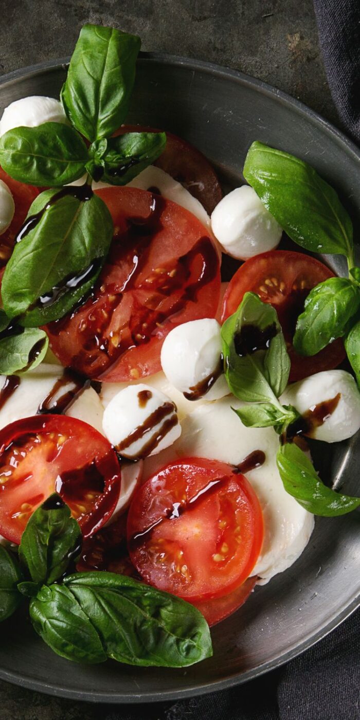 Sliced tomatoes, mozzarella, and fresh basil drizzled with balsamic, arranged as a light side dish for lemon pepper chicken