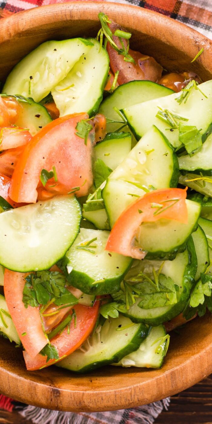 Bowl of cucumber and tomato salad with basil and red onion, served as a side for lemon pepper chicken.