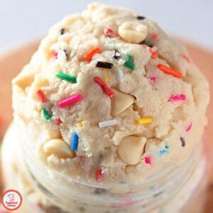 A jar of edible funfetti cookie dough with a spoon.