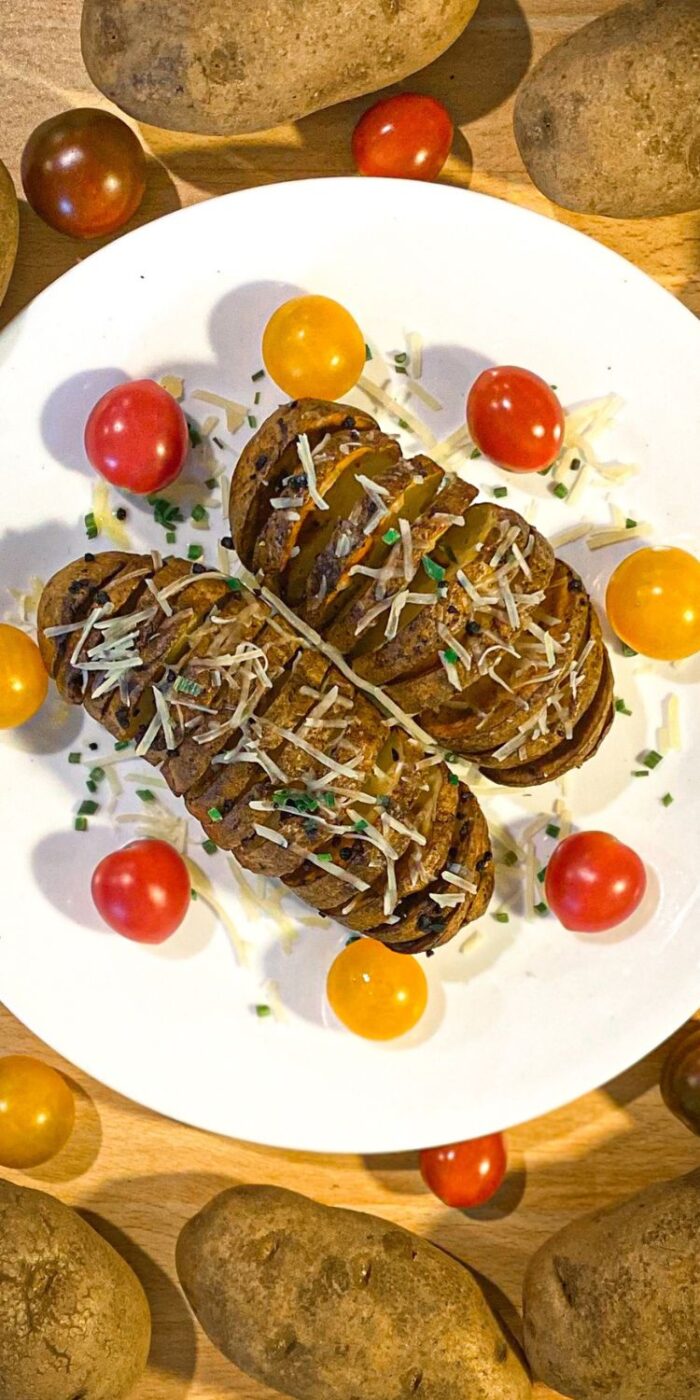 Golden, crispy Hasselback potatoes cooked in an air fryer, garnished with fresh herbs and melted butter.