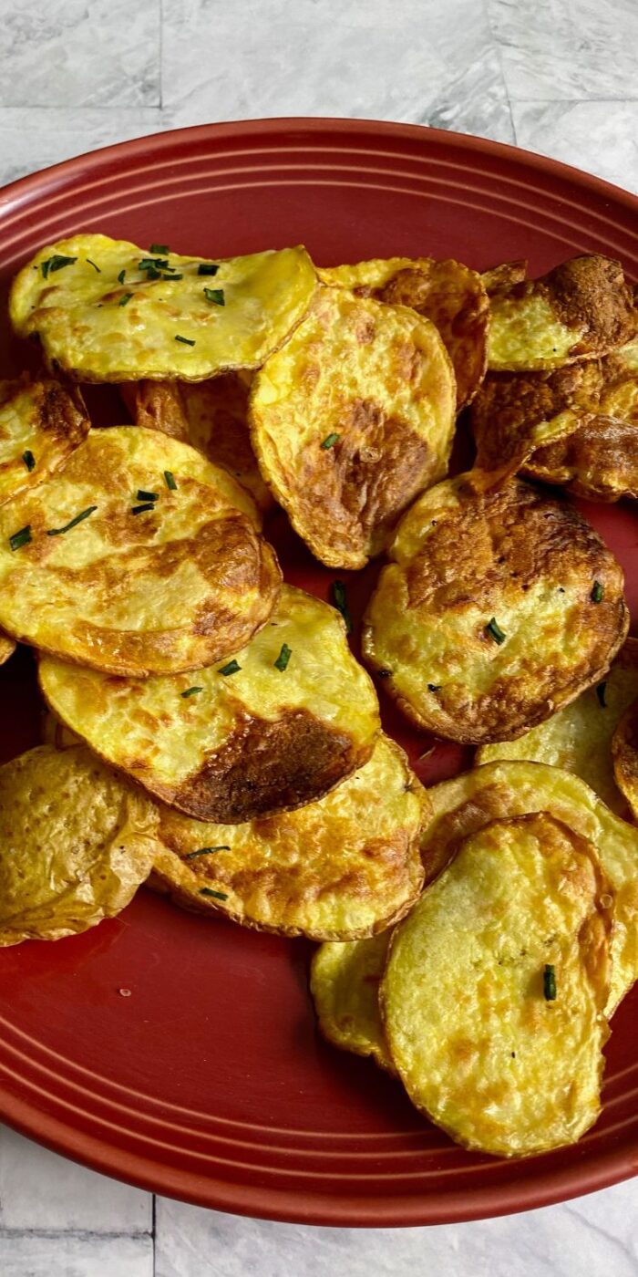 A bowl of golden, crispy homemade potato chips made in the air fryer, ready to enjoy as a healthy snack.