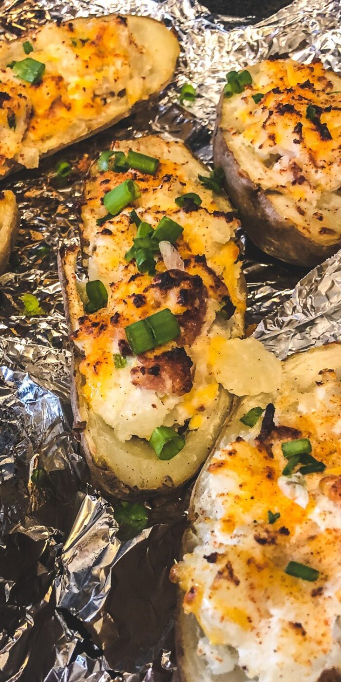 A plate of golden, crispy twice-baked potatoes stuffed with creamy cheese, bacon, and green onions, ready to serve.