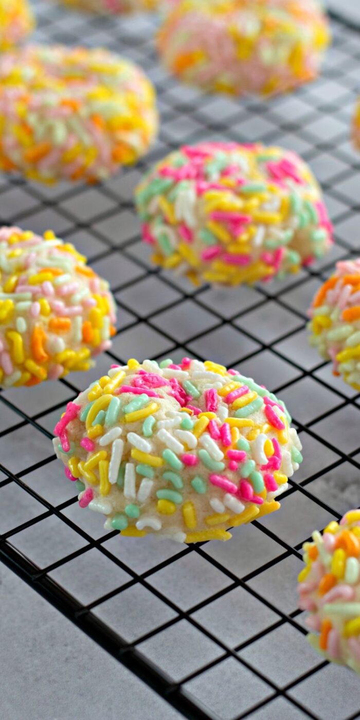 Sugar cookies with sprinkles arranged on a cooling rack.