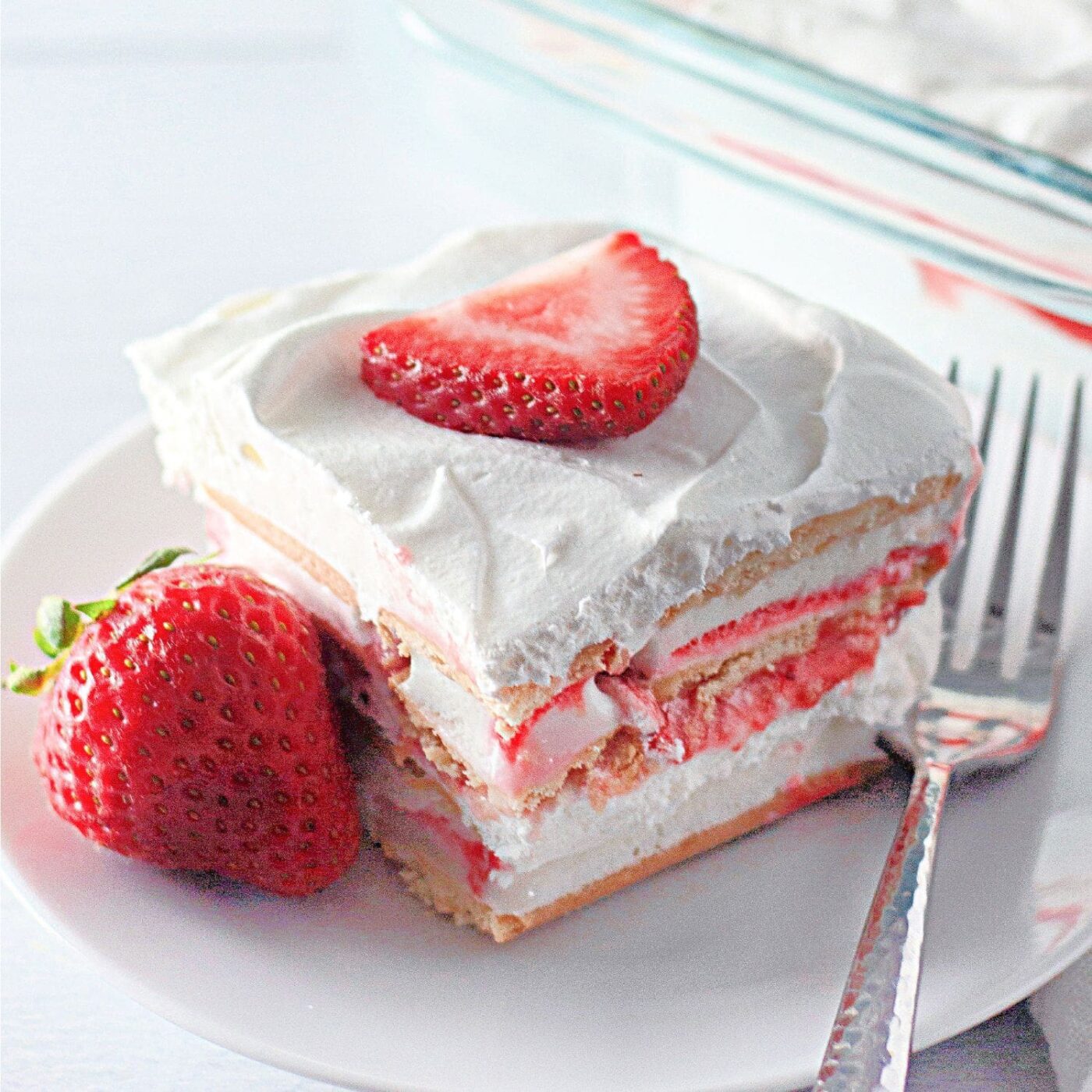 Slice of easy strawberry ice cream cake on a white plate.​