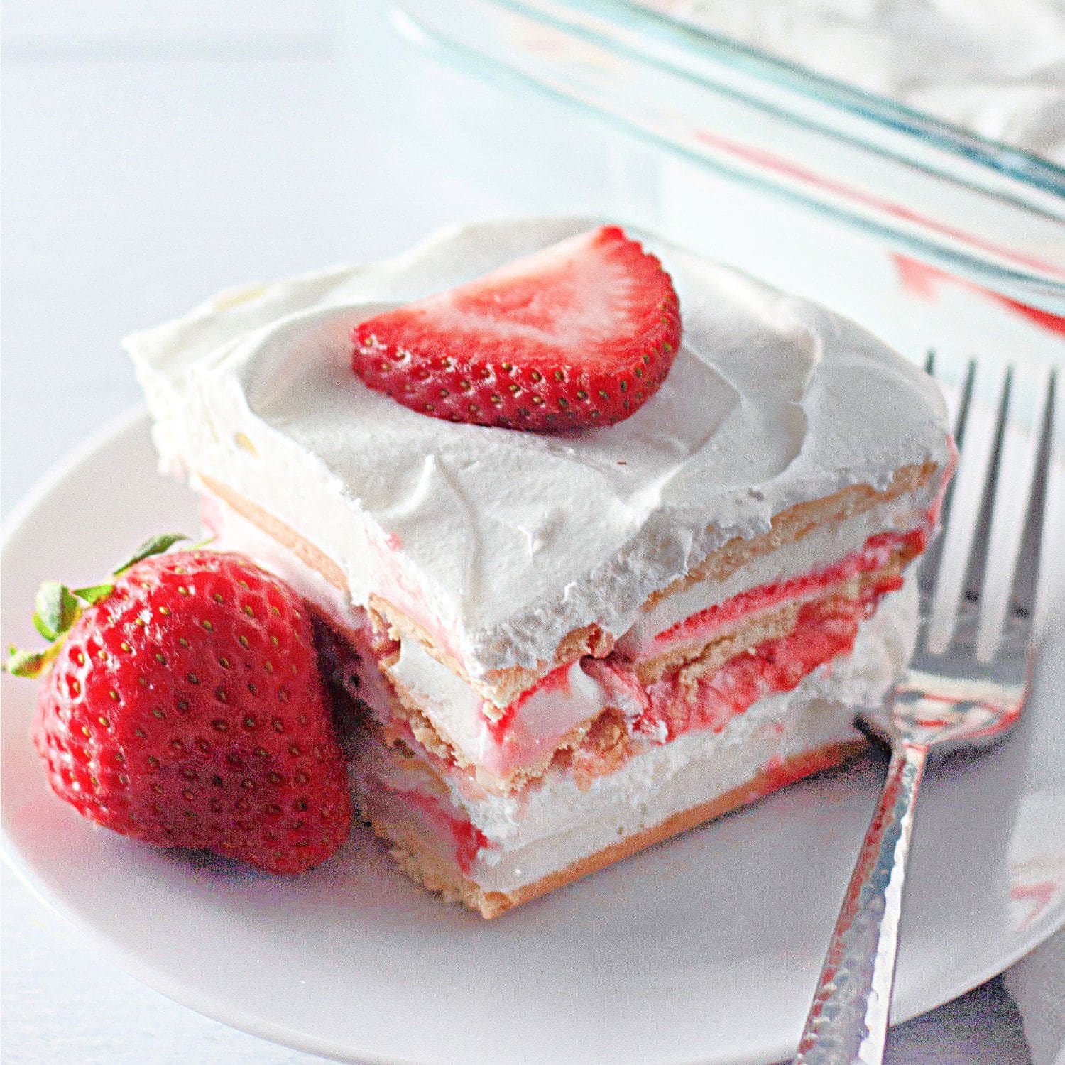 Slice of easy strawberry ice cream cake on a white plate.​