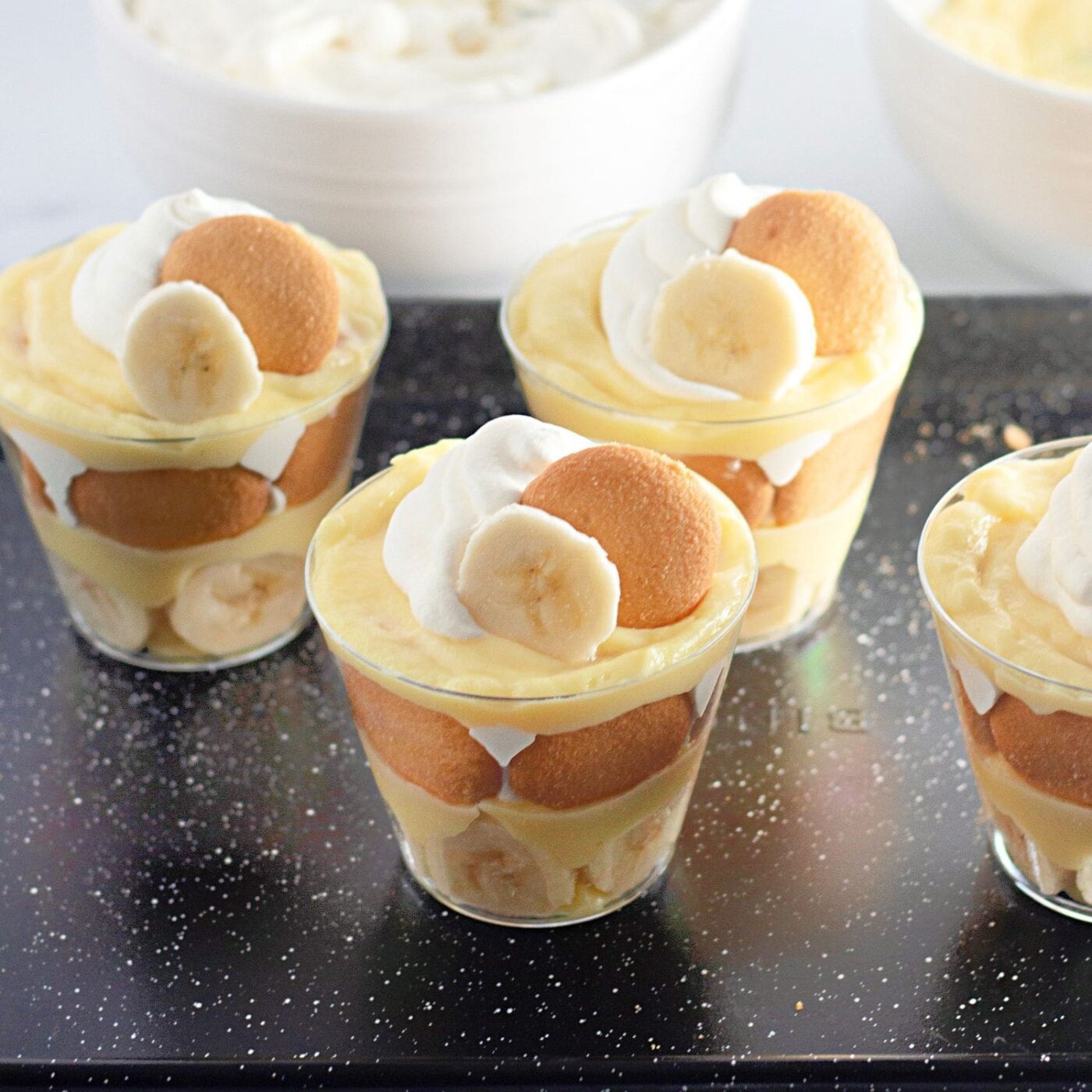Mini banana pudding cups layered with vanilla pudding and bananas.