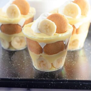 Banana pudding party desserts topped with cookies and whipped cream.