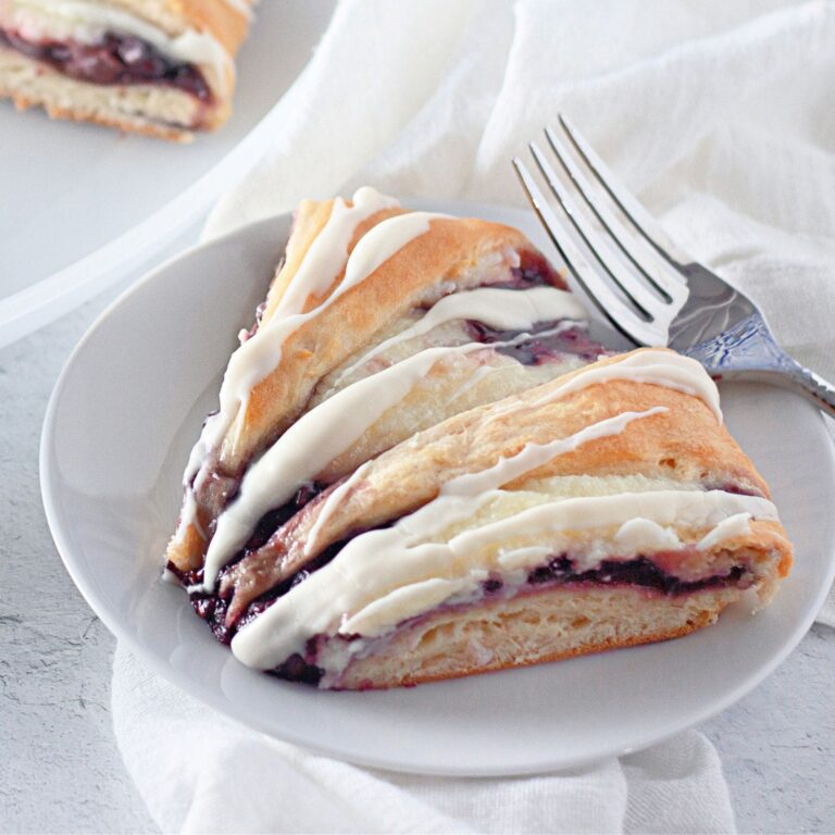 Flaky crescent roll pastry ring filled with raspberry cream cheese and glaze.