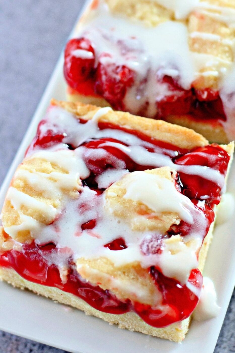 A pan of cherry pie bars with a beautiful vanilla glaze.