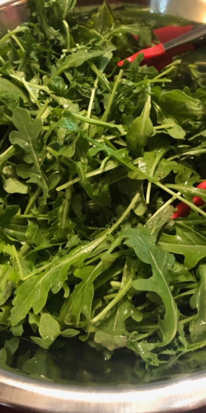 A fresh and healthy arugula salad with dressing, perfect for a light meal or side dish.