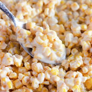 Bowl of creamed corn with a sprinkle of herbs.​