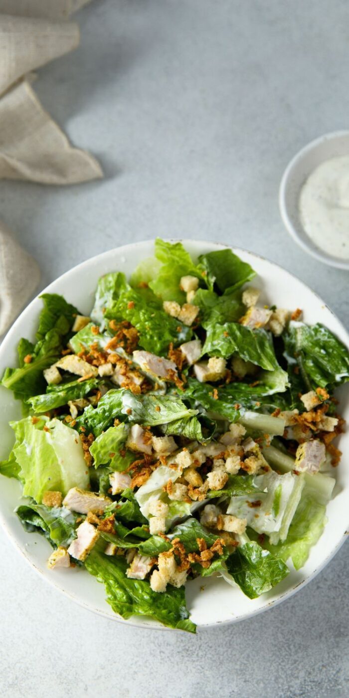 A classic Caesar salad with homemade creamy dressing, fresh romaine, and crunchy croutons, served on a white plate.