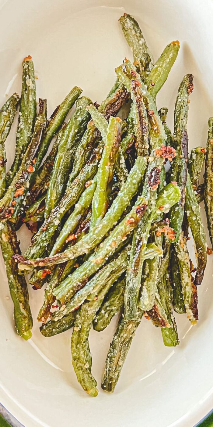 Golden and crispy roasted green beans topped with Parmesan cheese and garlic for a flavorful side dish.