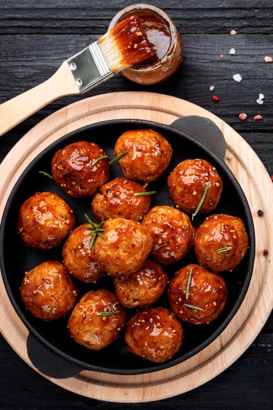 A serving bowl filled with glossy grape jelly meatballs, garnished with fresh parsley.