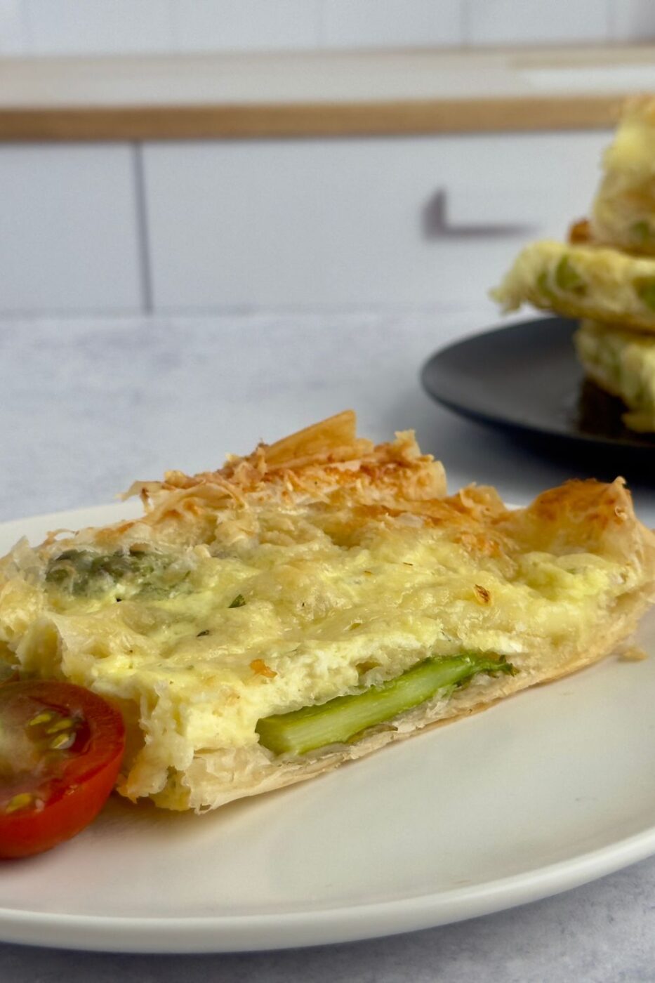 A golden-brown phyllo tart topped with asparagus spears and melted Camembert cheese.