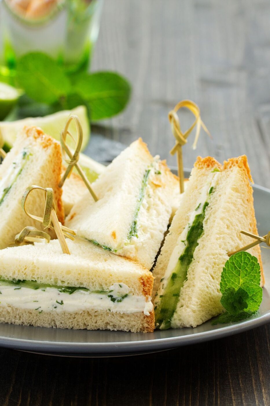 A plate of fresh open-faced cucumber sandwiches garnished with dill.