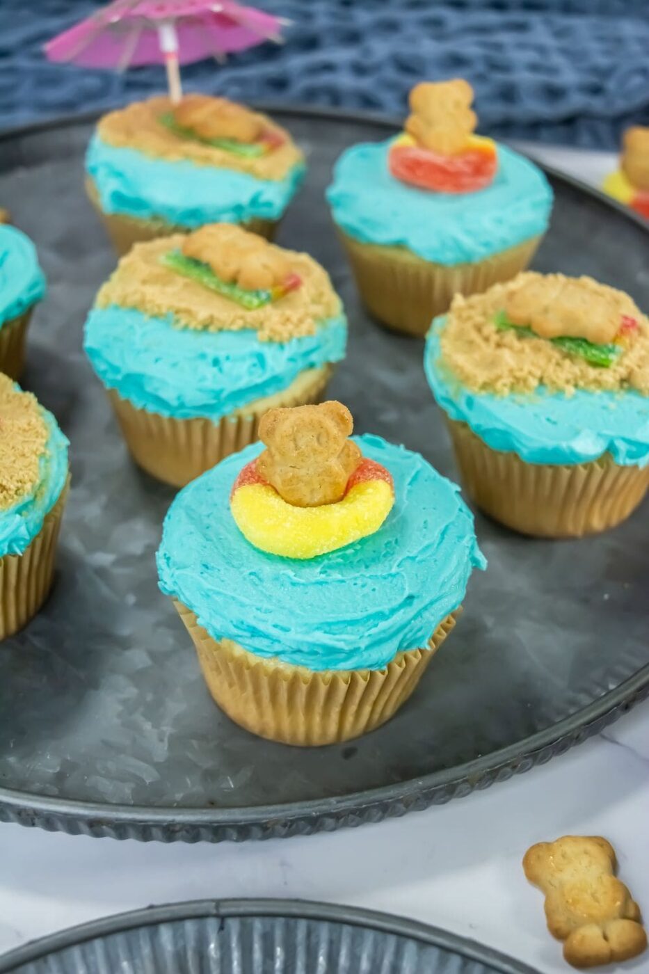 A colorful dessert cup with layers of crushed cookies, creamy filling, Teddy Grahams, and peach rings.