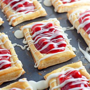 Recipe card image of cherry puff pastry danishes topped with glaze.