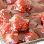 Cranberry sauce meatballs in glass dish, cooked in crockpot.