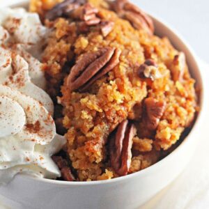 Recipe card layout featuring pumpkin cobbler in a bowl with pecans and whipped cream.